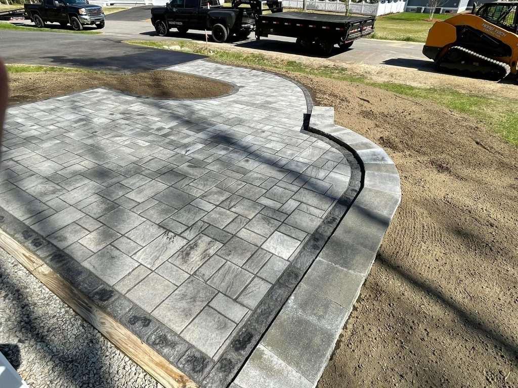 Curved granite curb and paver entrance apron under construction at a commercial lot